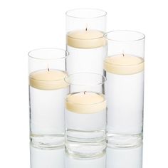 four clear glass vases filled with candles on top of each other in front of a white background