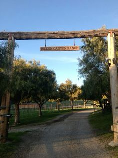 the entrance to hidden canyon ranch is shown in this photo, with trees and grass on either side