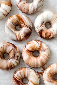 six donuts with brown and white swirls on them sitting on a sheet of wax paper