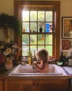 a young child is sitting in the kitchen sink