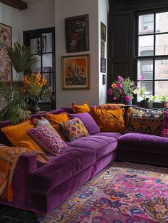 a living room filled with purple couches and lots of colorful pillows on top of it