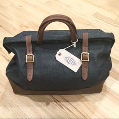 a black bag with brown straps and a white tag on the handle sitting on a wooden floor