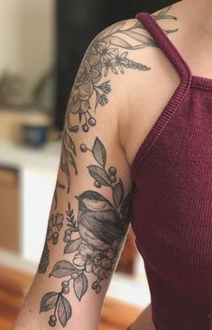 a woman's arm with flowers and birds on it, while she is wearing a red tank top