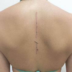 the back of a woman's neck with a small tattoo on her left side