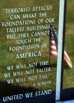 an american flag laying in the grass next to a plaque with words written on it