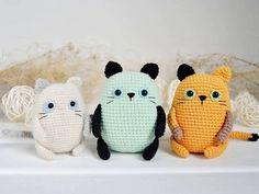 three crocheted cats sitting next to each other on top of a white shelf