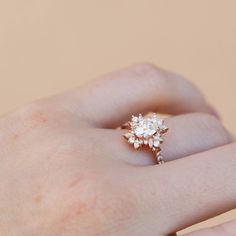 a woman's hand with a diamond ring on top of her finger and the other hand holding an engagement ring