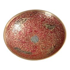 an ornate red and gold bowl with birds on the bottom, in front of a white background