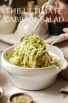 the ultimate cabbage salad in a white bowl is being served with a fork and garnish