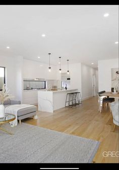 a living room filled with furniture next to a kitchen and dining room table on top of a hard wood floor