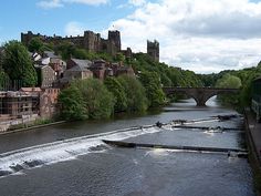 a river running through a lush green countryside next to a city with tall buildings on top of it