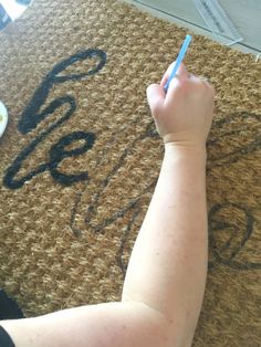 a person writing on a door mat with a marker