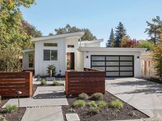 a white house with two garages and trees in the background