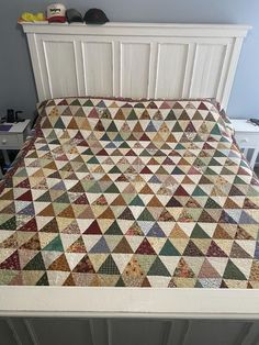 a bed with a quilt on top of it in a room next to a dresser