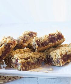 a white plate topped with cookies and bars on top of a wooden table next to a cup