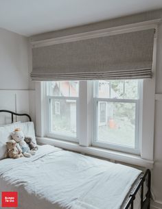 a white bed sitting under two windows in a bedroom