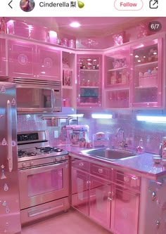 a pink kitchen with stainless steel appliances and glass cabinet doors that have lights on them