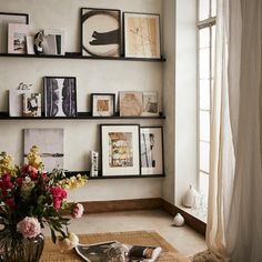 a vase with flowers sitting on top of a table in front of a wall filled with pictures