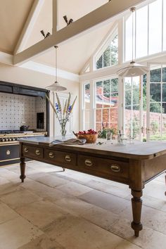 a kitchen with an old fashioned table in the center and lots of windows above it