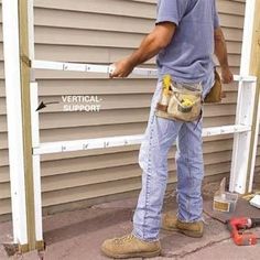 a man standing on the side of a building with tools in his hand and measuring tape