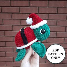 a hand holding a small crocheted turtle wearing a santa hat