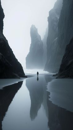 a person standing in the middle of a body of water near some rocks and cliffs