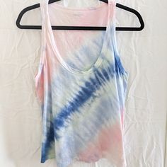 a tie dye tank top hanging on a hanger in front of a white wall