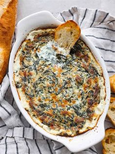 a bowl of spinach dip with bread on the side