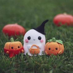 three small pumpkins with faces on them sitting in the grass