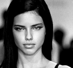 a black and white photo of a woman with long dark hair wearing a tank top