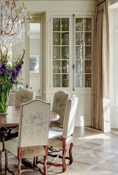 a dining room table with chairs and a chandelier hanging from the ceiling above it