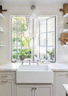 a white kitchen with an open window, sink and countertop area in front of it