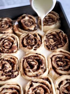 cinnamon rolls in a baking pan being drizzled with icing