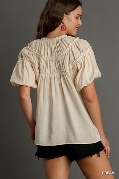 Experience effortless style and comfort with our Kate Modal Pleated Split Neck Ruffle Top in Cream! Made from soft modal fabric, this top features delicate pleating, a flattering split neck, and charming ruffle details. Elevate any outfit with this versatile and elegant top. Relaxed Fit V-neck Top With Ruffles, Spring V-neck Puff Sleeve Top With Ruffles, Feminine Flutter Sleeve Top With Ruffle Hem, Solid Color Tops With Ruffle Hem And Ruffle Sleeves, Flowy Smocked Bodice Top With Flutter Sleeves, Feminine Top With Smocked Bodice And Flutter Sleeves, Feminine Blouse With Ruffle Sleeves And Relaxed Fit, Feminine Tops With Smocked Bodice And Flutter Sleeves, Spring V-neck Peasant Top With Ruffles