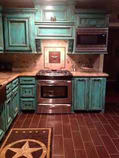 a kitchen with green cabinets and an area rug on the floor in front of the stove