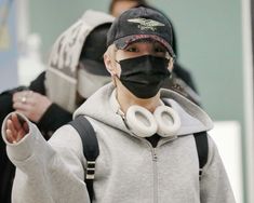 a young man wearing a black mask and earbuds with his hands in the air