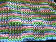 a crocheted blanket is shown with multicolored stripes