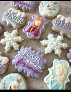 frozen princess cookies decorated with royal icing and snowflakes are displayed on a table