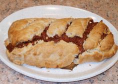 a white plate topped with a piece of meat filled pastry on top of a counter