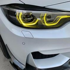 the front end of a white car with yellow lights on it's headlight