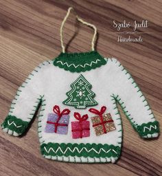 an ugly sweater ornament is hanging on a wooden table with presents in it