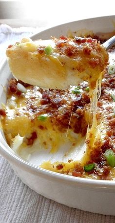 a close up of a casserole in a white bowl with a serving spoon