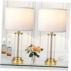 two lamps sitting on top of a table next to a vase with flowers in it