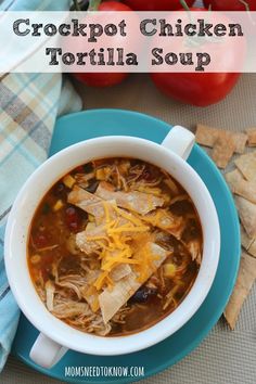 crockpot chicken tortilla soup in a blue bowl with crackers on the side