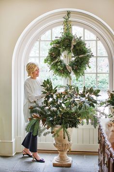 a woman is standing in front of a wreath on the door way to her home