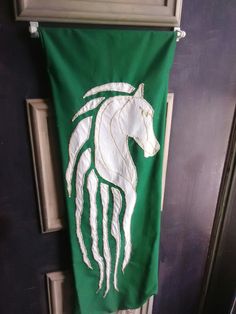 a green towel with a white horse on it hanging from the front door, next to an open door