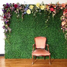 a chair sitting in front of a green wall with flowers on it and a wooden floor