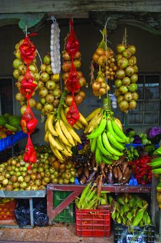 an outdoor fruit stand with bananas and other fruits hanging from it's hooks,