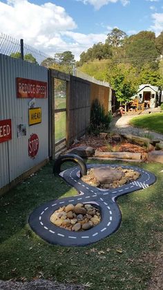 an outdoor play area with rocks and gravel in the shape of a race track on grass