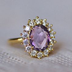 an oval shaped amethorate and diamond ring on top of a white cloth